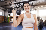 Portrait of smiling young caucasian athlete lifting dumbbell during bicep curl workout in gym. Strong, fit, active woman training with weights in health and sport club. Weightlifting exercise routine