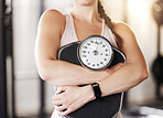 Closeup of one unknown caucasian athlete holding weight scale after workout in gym. Strong, fit, active woman maintaining diet during training and exercise in health and sport club. Healthy and toned