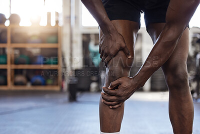 Closeup of one unknown african american athlete suffering from knee injury during workout in gym. Strong, fit, active black man feeling pain in leg joint during training and exercise at health club