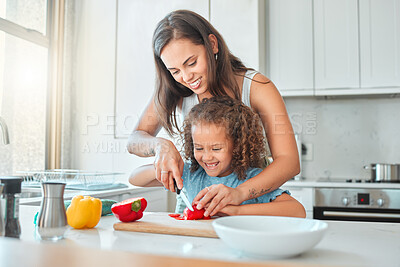 Smiling mixed race mother and small daughter chopping vegetables and preparing vegetarian meal in the kitchen at home
