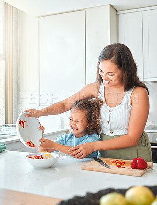 Buy stock photo Cheerful mother and little daughter having fun cooking together in the kitchen. Mom and child cutting vegetables preparing a vegetarian meal