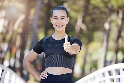 Happy female athlete showing thumbs up while out for a run or jog outdoors. Fit young woman smiling and looking satisfied during her workout at the park