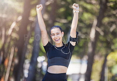 Portrait of cheerful young mixed race female athlete celebrating a goal, making a winner gesture with arms raised after a workout in nature