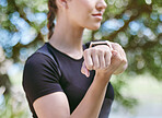 Close up of female athlete stretching her arms during workout in nature on a sunny day. Fit sportswoman doing warmup exercise before her run in nature