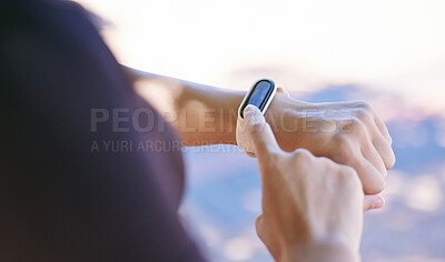 Close up of young female athlete using app on smart watch while training outdoors. Sportswoman touching watch screen while tracking her progress while out for a run