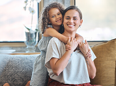Portrait of Little girl embracing her mother from behind showing love and affection while sitting on the couch at home. Sweet moment between mother and daughter on mothers day
