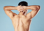 Rearview young mixed race man standing shirtless in studio isolated against a blue background. Unrecognizable male athlete standing with his hands behind his head during a break from his workout