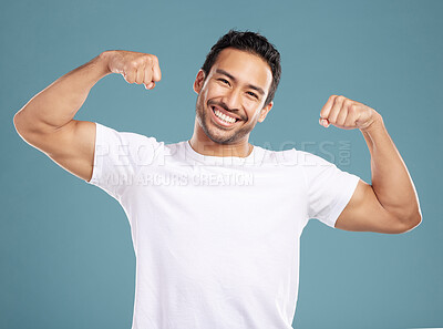 Buy stock photo Handsome young mixed race man flexing his biceps while standing in studio isolated against a blue background. Athletic hispanic male showing his muscles, proud of is health and fitness lifestyle