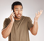Handsome young mixed race man looking irritated, aggravated or agitated while using his phone in studio isolated against a grey background. Displeased hispanic male making a call to complain or argue