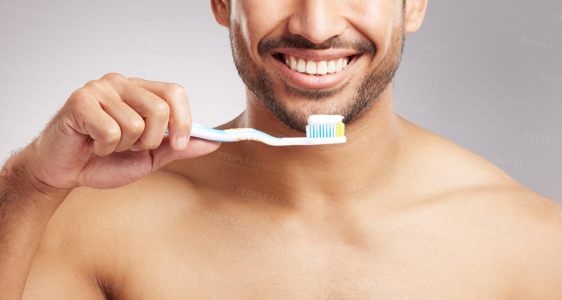 Buy stock photo Closeup young mixed race man shirtless in studio isolated against a grey background. Hispanic male brushing his teeth. Taking caring of mouth and oral hygiene to promote dental health and healthy gums