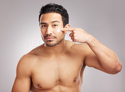 Buy stock photo Handsome young mixed race man shirtless in studio isolated against a grey background. Hispanic male applying moisturizer lotion to his face. Looking confident and happy with his daily skincare regime