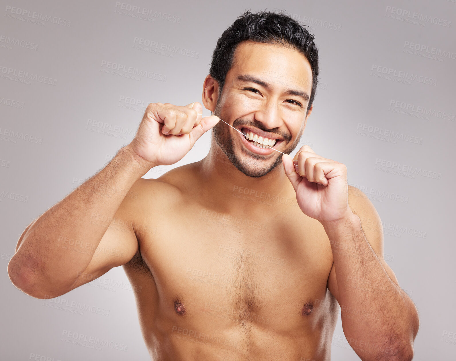 Buy stock photo Closeup young mixed race man shirtless in studio isolated against a grey background. Hispanic male using dental floss. Taking caring of mouth and oral hygiene to promote healthy teeth and gums