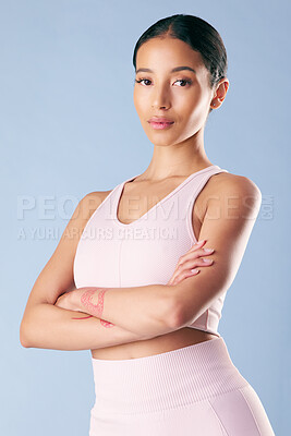 Buy stock photo Mixed race fitness woman standing with her arms crossed in studio against a blue background. Beautiful young hispanic female athlete looking confident and exercising or working out. Health and fitness