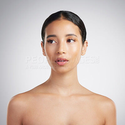 A beautiful young mixed race woman with glowing skin posing against grey copyspace background. Hispanic woman with natural looking eyelash extensions is a confident natural beauty in a studio