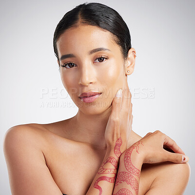 Buy stock photo Portrait of a beautiful mixed race woman touching smooth soft skin in a studio. Hispanic model with healthy natural glowing skin looking confident against grey copyspace while doing routine skincare