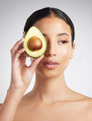 A gorgeous mixed race woman holding an avocado. Hispanic model promoting the skin benefits of a healthy diet against a grey copyspace background