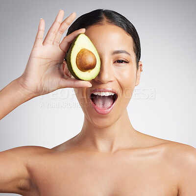 Studio Portrait of a happy smiling mixed race woman holding an avocado. Hispanic model promoting the skin benefits of a healthy diet against a grey copyspace background