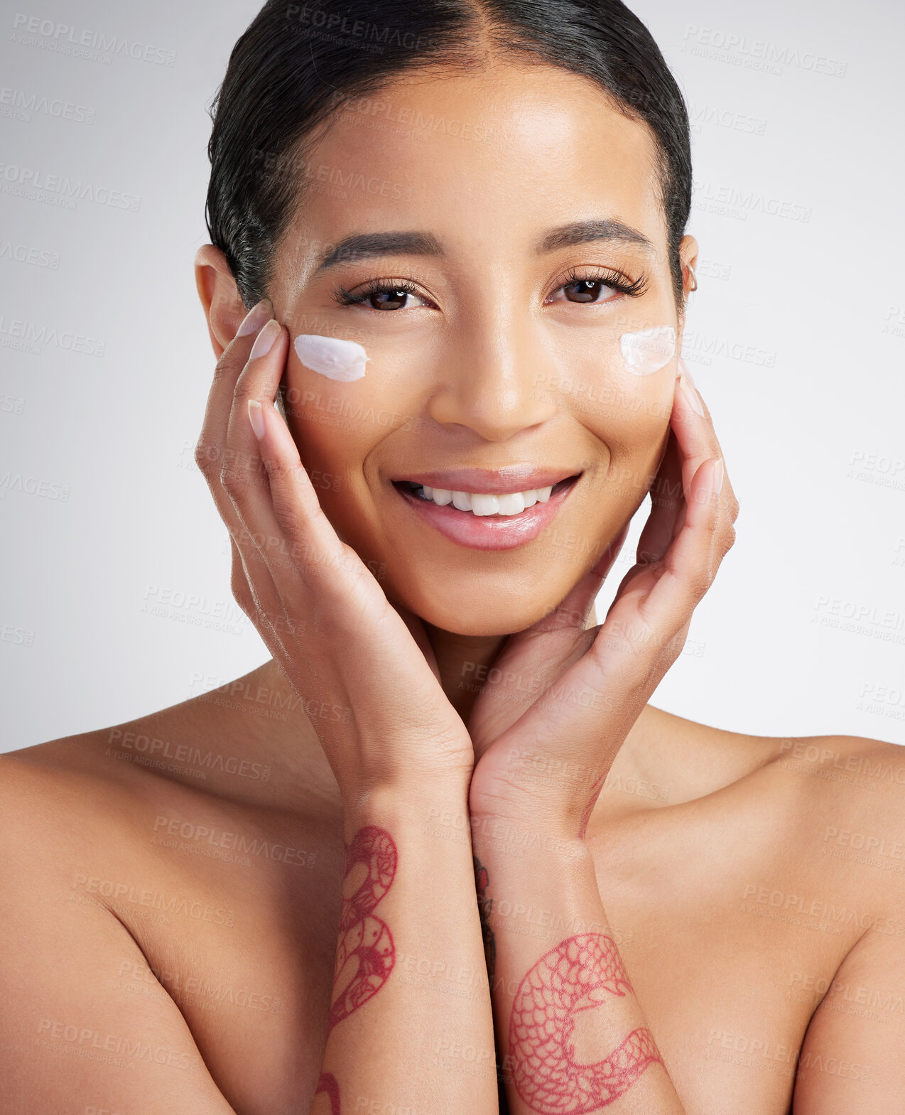 Buy stock photo Studio Portrait of a beautiful smiling mixed race woman applying cream to her face. Hispanic model with glowing skin using sunscreen against a grey copyspace background