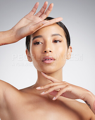 A beautiful young mixed race woman with glowing skin posing against grey copyspace background. Young confident woman doing a routine selfcare grooming routine with glowing radiant skin
