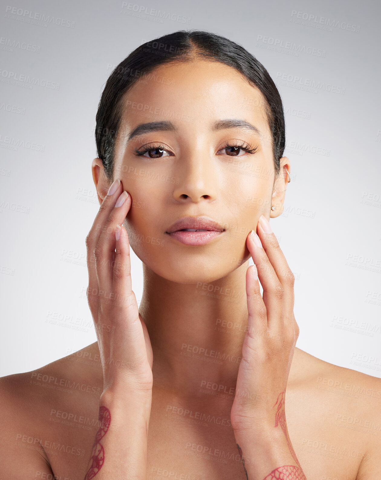 Buy stock photo Portrait of a beautiful mixed race woman touching smooth soft skin in a studio. Hispanic model with healthy natural glowing skin looking confident against grey copyspace while doing routine skincare