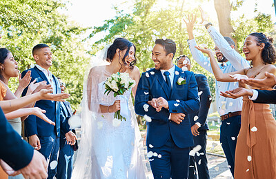 Buy stock photo Wedding guests throwing rose petals confetti tradition over bride and groom on their special day. Newlywed couple walking past friends and family
