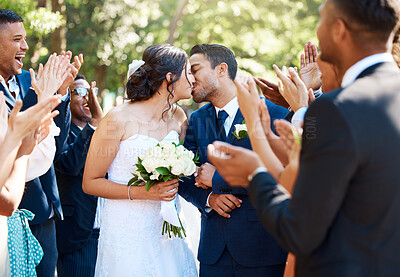 Buy stock photo Bride and groom kissing after wedding ceremony while friends and family clap and celebrate their wedding day