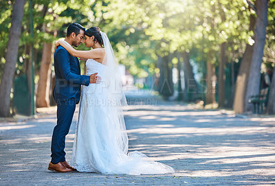 Buy stock photo Young bride and groom enjoying romantic moments outside on a beautiful summer day in nature. Full length shot of newlywed couple touching foreheads while standing close