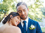 Joyful bride leaning on grooms shoulder while standing outside. Loving newlywed couple enjoying romantic moments together. Feeling safe and secure