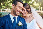 Joyful bride and groom leaning against each other while enjoying romantic moments on wedding day in park on a sunny day