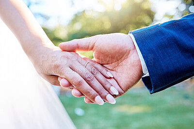 Buy stock photo Close up hands of newlywed couple standing outside on a sunny day. Groom holding his brides hand with wedding band