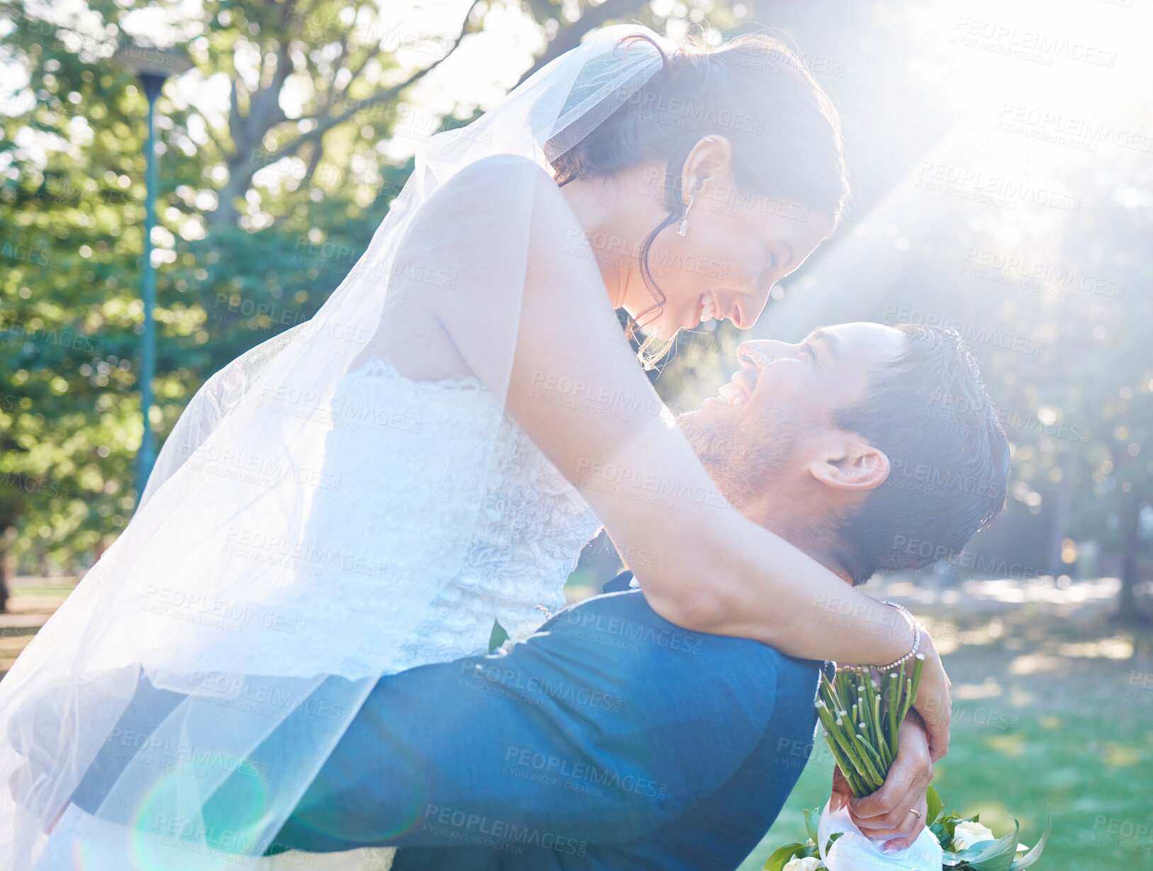 Buy stock photo Close up of groom lifting bride up while looking into each others eyes on a sunny day in nature. Newlyweds enjoying romantic moments on their wedding day