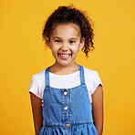 Studio portrait mixed race girl looking standing alone isolated against a yellow background. Cute hispanic child posing inside. Happy and cute kid smiling and looking carefree in casual clothes