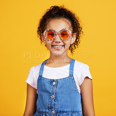 Studio portrait mixed race girl wearing funky sunglasses Isolated against a yellow background. Cute hispanic child posing inside. Happy and carefree kid with an imagination for being a fashion model