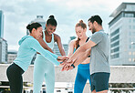 Diverse group of happy sporty people stacking hands together in pile to express unity and support. Motivated athletes huddled in circle for encouraging workout pep talk. Joining for collaboration, team spirit and dedication for training workout in city