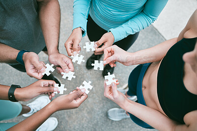 Buy stock photo Closeup of diverse group of people from above assembling jigsaw puzzle pieces together. Hands of multiracial people working in synergy to problem solve. Using dedicated teamwork to support and help find common solutions
