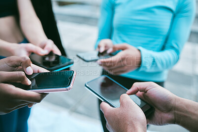 Buy stock photo Closeup of diverse group of sporty people using cellphones with blank screens in synchronicity while standing in a circle around each other. Hands of athletes browsing online and searching the internet in a huddle. Downloading and sharing media