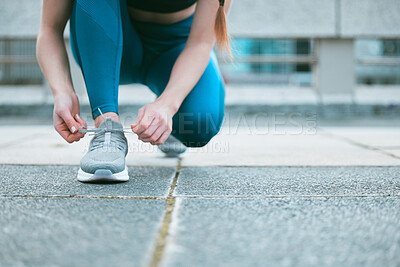 Buy stock photo Closeup of one caucasian woman tying her shoelaces while exercising outside. Athlete fastening sneaker footwear for a comfortable fit and to prevent tripping during a training workout in the city