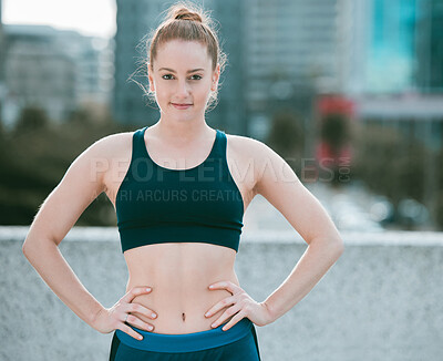 Buy stock photo Portrait of one confident young caucasian woman standing with hands on hips ready for exercise outdoors. Determined female athlete looking focused and motivated for training workout in the city