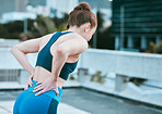 One caucasian woman from behind holding sore lower back while exercising outdoors. Female athlete suffering with painful spine injury from fractured joint and inflamed muscles during workout. Struggling with stiff body cramps causing discomfort and strain
