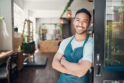 Buy stock photo Portrait of one happy young hispanic waiter standing with his arms crossed at the doorway of a store or cafe. Friendly man and coffeeshop owner managing a successful restaurant startup