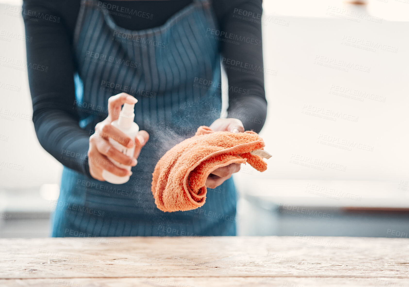 Buy stock photo Closeup of one woman spraying antibacterial cleaner from a bottle onto a cloth to disinfect and wipe table in a cafe or store. Hands of a shop assistant sanitising surfaces to maintain hygiene and prevent the spread of covid germs