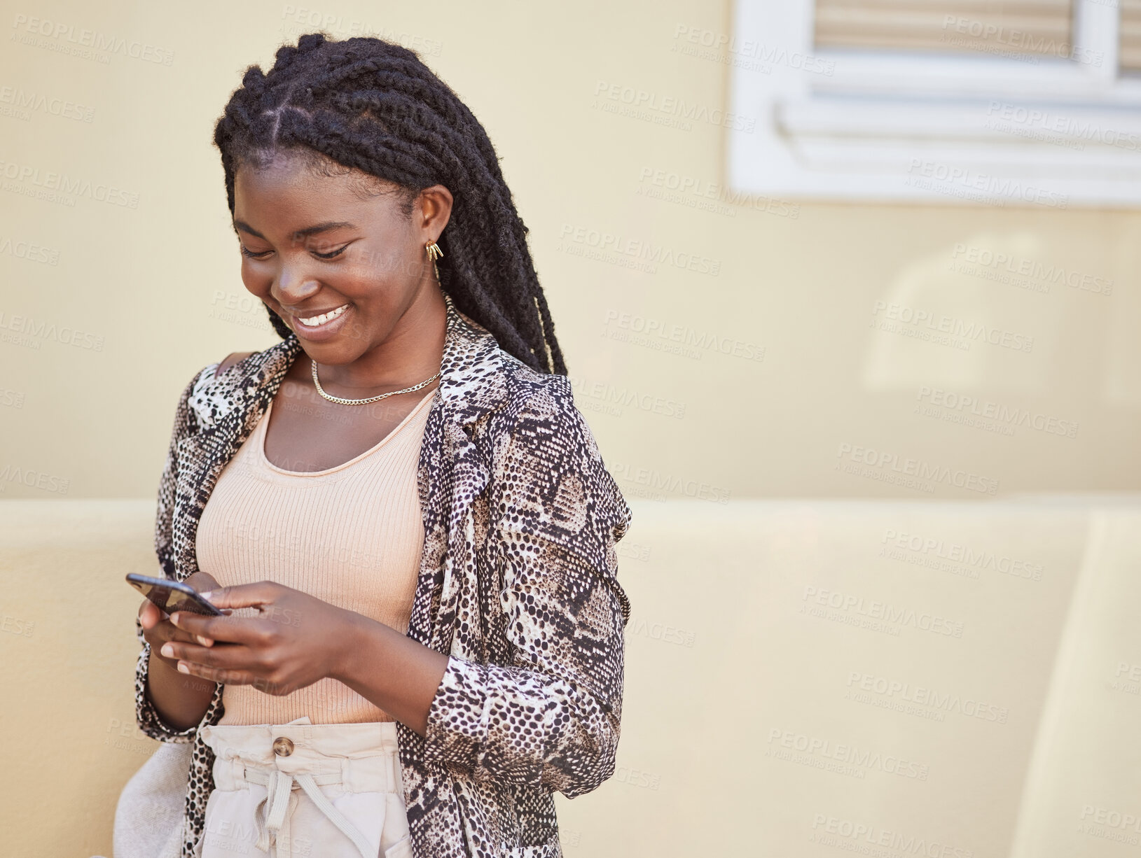 Buy stock photo Happy african american woman using smartphone while walking on city street. Stylish woman smiling while sending a text or chatting on social media