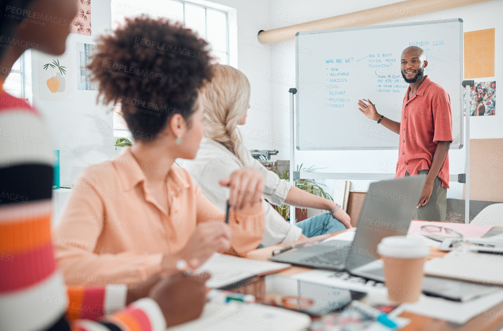 Buy stock photo Group of diverse businesspeople having a meeting in a modern office at work. Young african american businessman smiling while doing a presentation of an idea on a whiteboard in a boardroom with colleagues. Businesspeople planning together