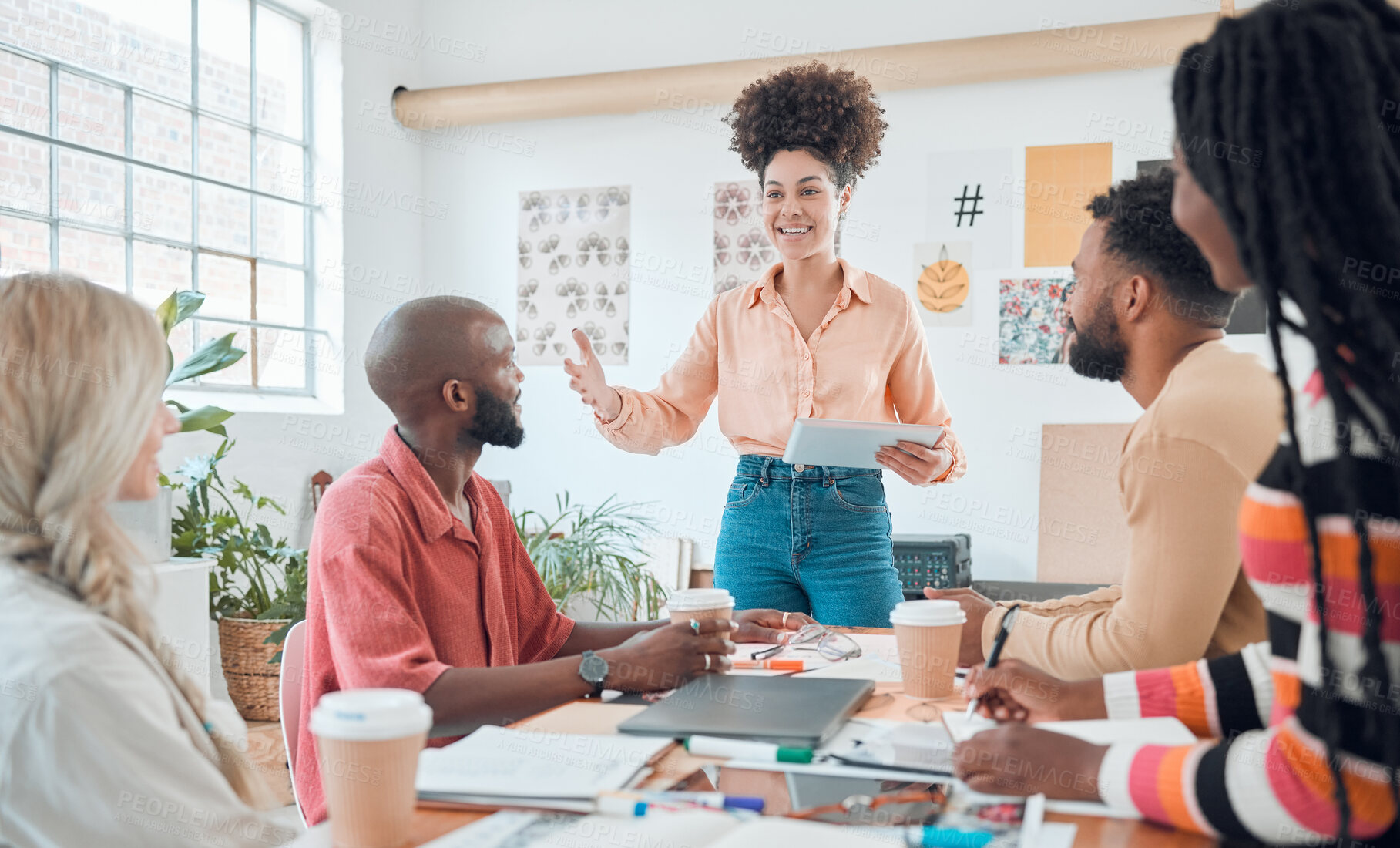 Buy stock photo Group of diverse businesspeople having a meeting in a modern office at work. Young happy hispanic businesswoman with a curly afro doing a presentation of an idea using a digital tablet in a boardroom with colleagues. Businesspeople planning together