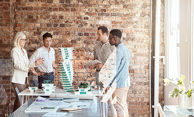 Buy stock photo Group of diverse architects discussing plans, blueprints and schematics during a meeting in their office boardroom. Business people brainstorming and planning their upcoming project development