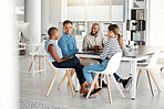 Group of diverse happy businesspeople having a meeting in an office at work. Young african american businesswoman talking to her colleagues while sitting at a table. Businesspeople planning together