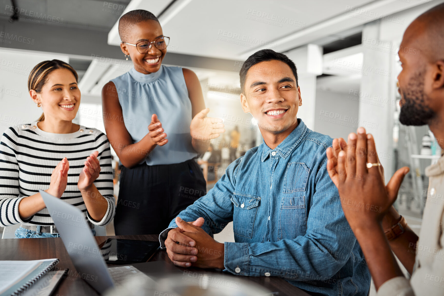 Buy stock photo Group of diverse businesspeople having a meeting in an office at work. Happy business professionals clapping for their colleagues achievement together. Happy businessman being applauded by his coworkers