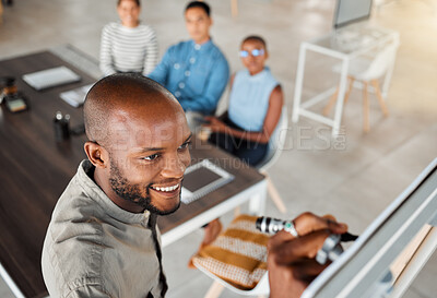 Group of diverse businesspeople having a meeting in an office at work. Young happy african american businessman smiling while writing an idea on a whiteboard in a boardroom with colleagues. Businesspeople planning together
