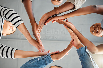 Buy stock photo Group of businesspeople forming a circle with their hands in an office at work. Colleagues having fun and making a shape with their hands together. Coworkers showing support and motivation for each other