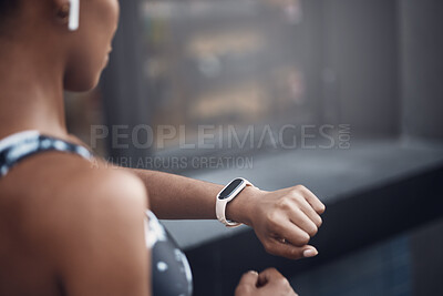 Closeup of one mixed race woman checking time on digital wristwatch with blank display screen while running outdoors. Female athlete wearing fitness tracker on arm to monitor progress, heart rate and calories burned during training exercise in the city